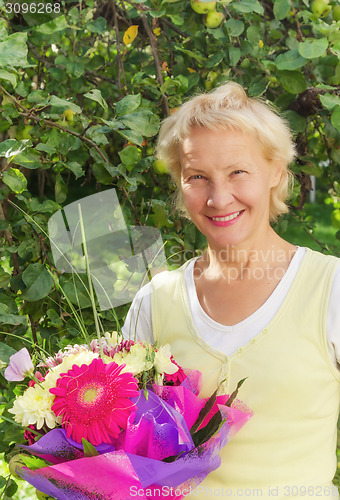 Image of Portrait of a woman in the garden with a bouquet of flowers