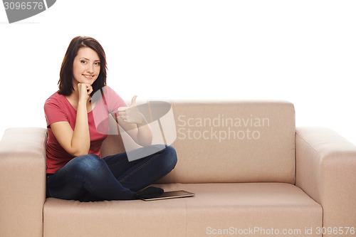 Image of Smiling woman sitting on the sofa and showing thumb up