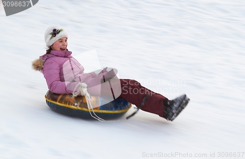 Image of happy teenage girl sliding down on snow tube