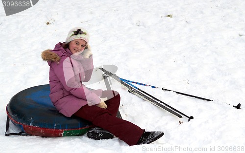 Image of happy teenage girl having a rest after sliding down on snow tube