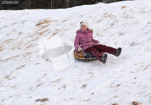 Image of happy teenage girl sliding down on snow tube