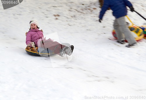 Image of happy teenage girl sliding down on snow tube