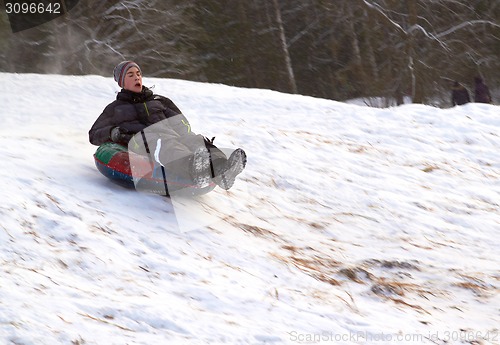 Image of happy teenage boysliding down on snow tube