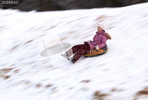 Image of happy teenage girl sliding down on snow tube