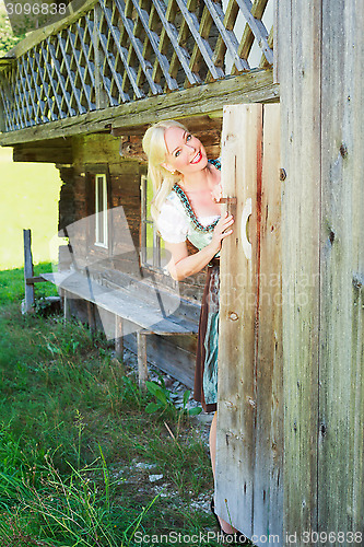 Image of Young woman in dirndl looks out of the toilet door