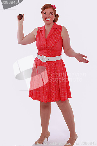 Image of Red-haired woman in red dress 60 years Style and obesity, poses with a Muffin