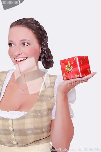 Image of Young woman in Dirndl and braided hair has a gift on the palm of her hand