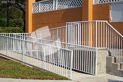 Image of handicap ramp with white railing and orange wall