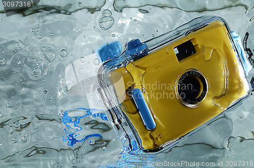 Image of Photo of yellow waterproof camera in water with splash.