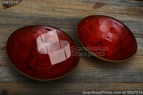 Image of two ceramic red empty bowls on a wooden