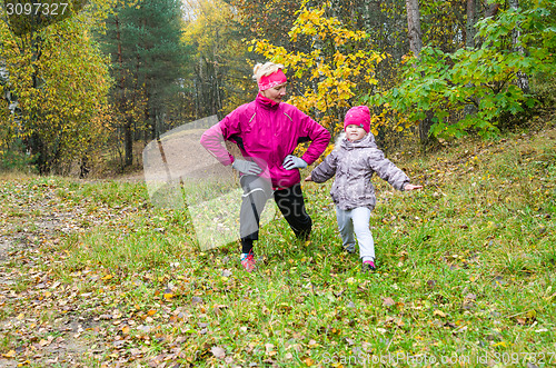 Image of Woman with girl doing aerobics in the autumn park