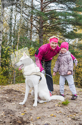 Image of Granny with her granddaughter and a dog walk in autumn Park  