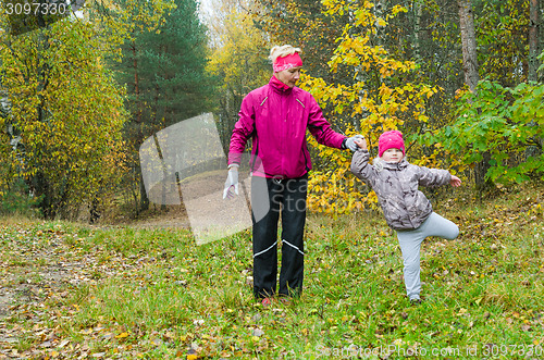 Image of Woman with girl doing aerobics in the autumn park