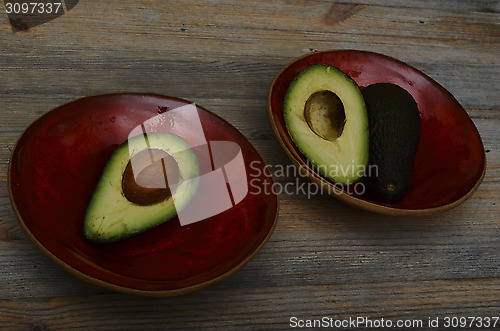 Image of avocado in two red ceramic bowl 