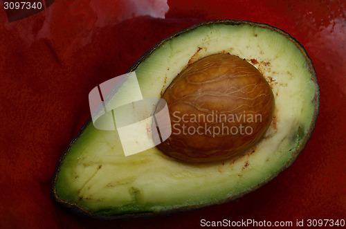 Image of fresh avocado half on a red ceramic dish