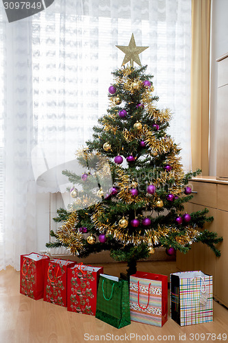 Image of Decorated christmas tree with yellow and violet balls 