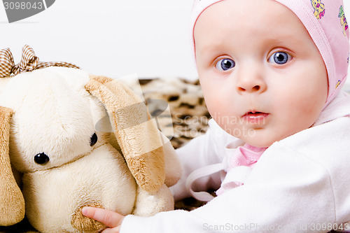 Image of blue-eyed baby with a soft toy. studio photo