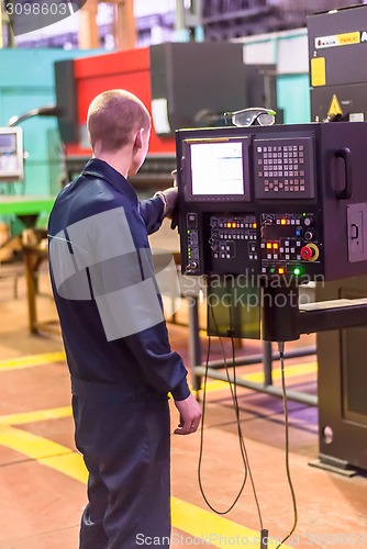 Image of Worker operates computerized metalworking machine