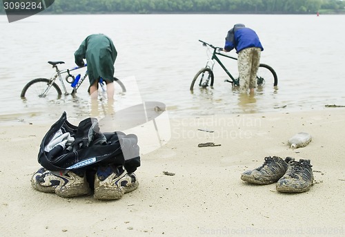 Image of Dirty cycle tourists wash bicycles from dirt