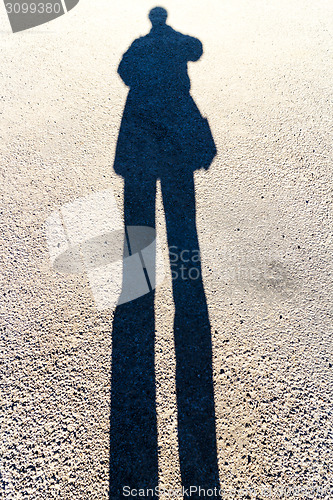 Image of Elongated Shadow of a Person Standing on the Road