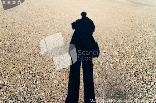 Image of Elongated Shadow of a Person Standing on the Road