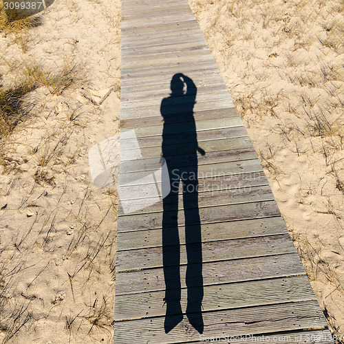 Image of Elongated Shadow Jumping Man on a Wooden Walkway