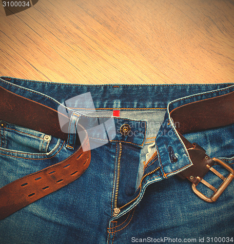 Image of Aged blue jeans with a leather belt