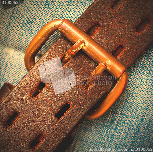 Image of clasped leather belt on jeans background