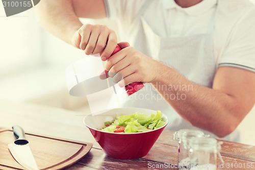 Image of close up of male hands flavouring salad in a bowl