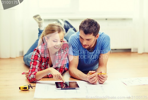 Image of smiling couple looking at tablet pc at home