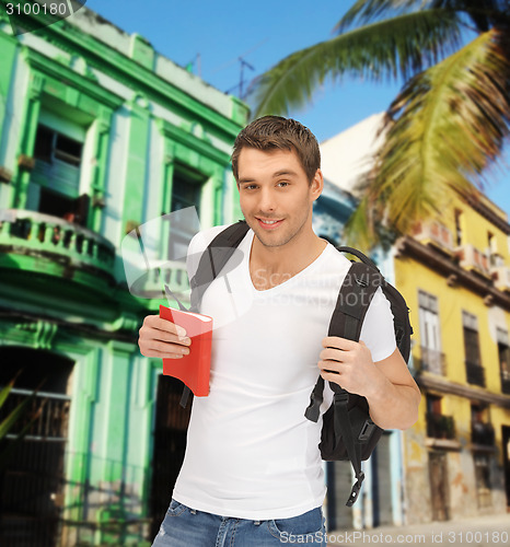 Image of happy young man with backpack and book travelling