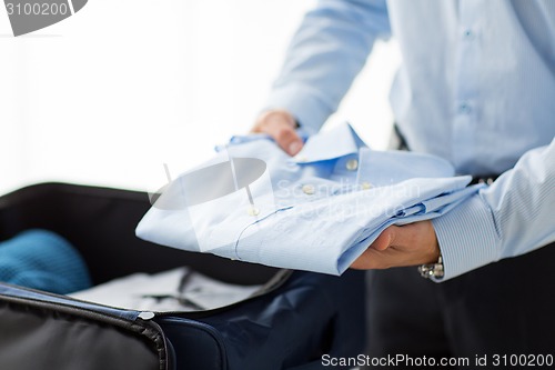 Image of businessman packing clothes into travel bag