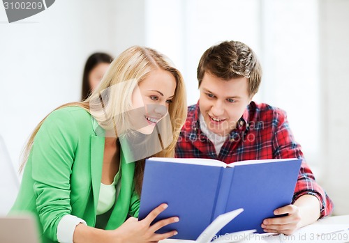 Image of girl and guy reading book at school