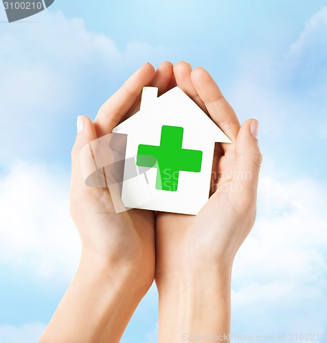 Image of hands holding paper house with green cross