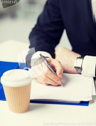 Image of businessman with coffee writing something