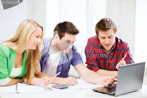 Image of smiling students looking at laptop at school