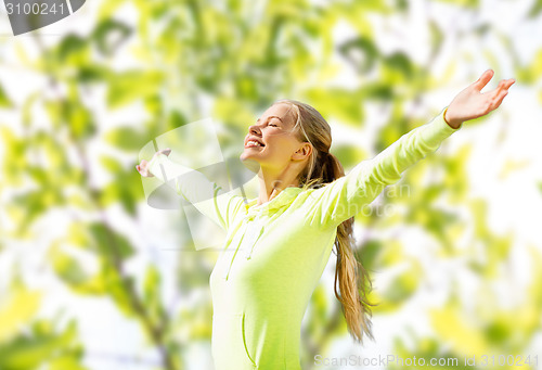 Image of happy woman in sport clothes raising hands