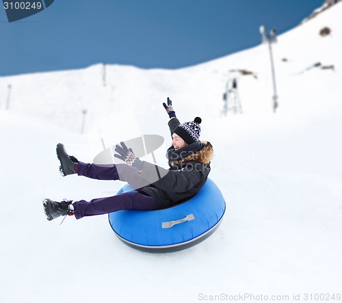 Image of happy young man sliding down on snow tube