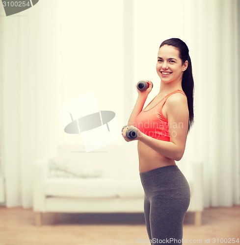 Image of young sporty woman with light dumbbells