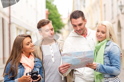 Image of group of smiling friends with map and photocamera