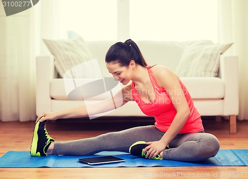 Image of smiling teenage girl streching on floor at home