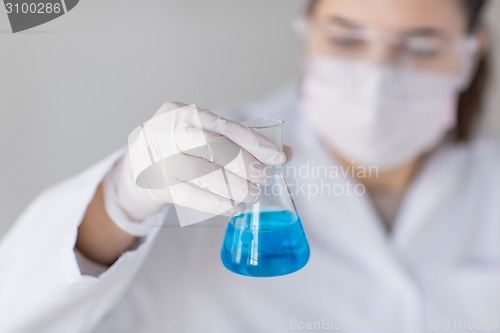 Image of close up of woman with flask making test in lab