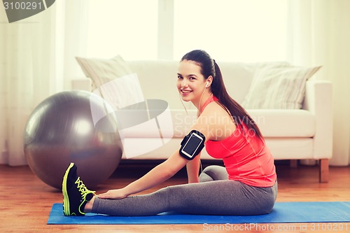 Image of smiling girl with armband execising at home