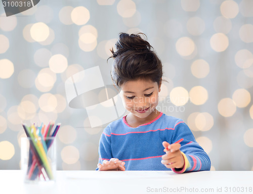 Image of happy little girl drawing with coloring pencils