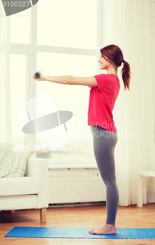 Image of smiling teenage girl exercising with dumbbells