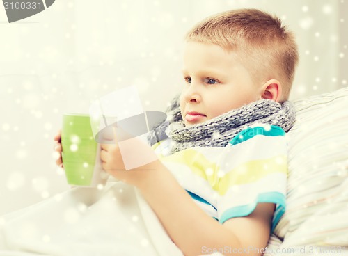 Image of ill boy with flu in bed drinking from cup at home