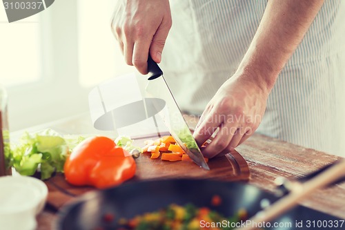 Image of close up of male hand cutting pepper on board