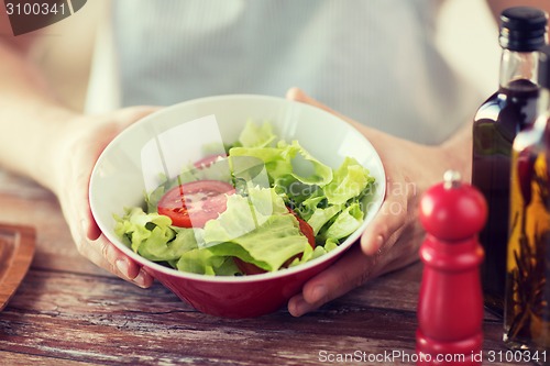 Image of close of male hand holding a bowl with salad