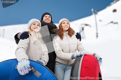 Image of group of smiling friends with snow tubes