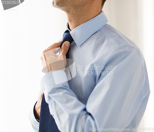 Image of close up of man in shirt adjusting tie on neck